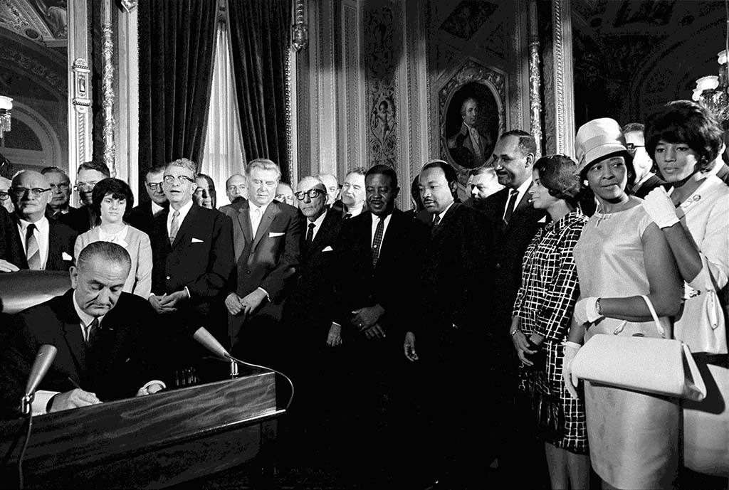 President_Lyndon_Johnson_signing_Voting_Rights_Act_with_Dr_Martin_Luthor_King_Jr_watching_Washington_DC_August_6_1965